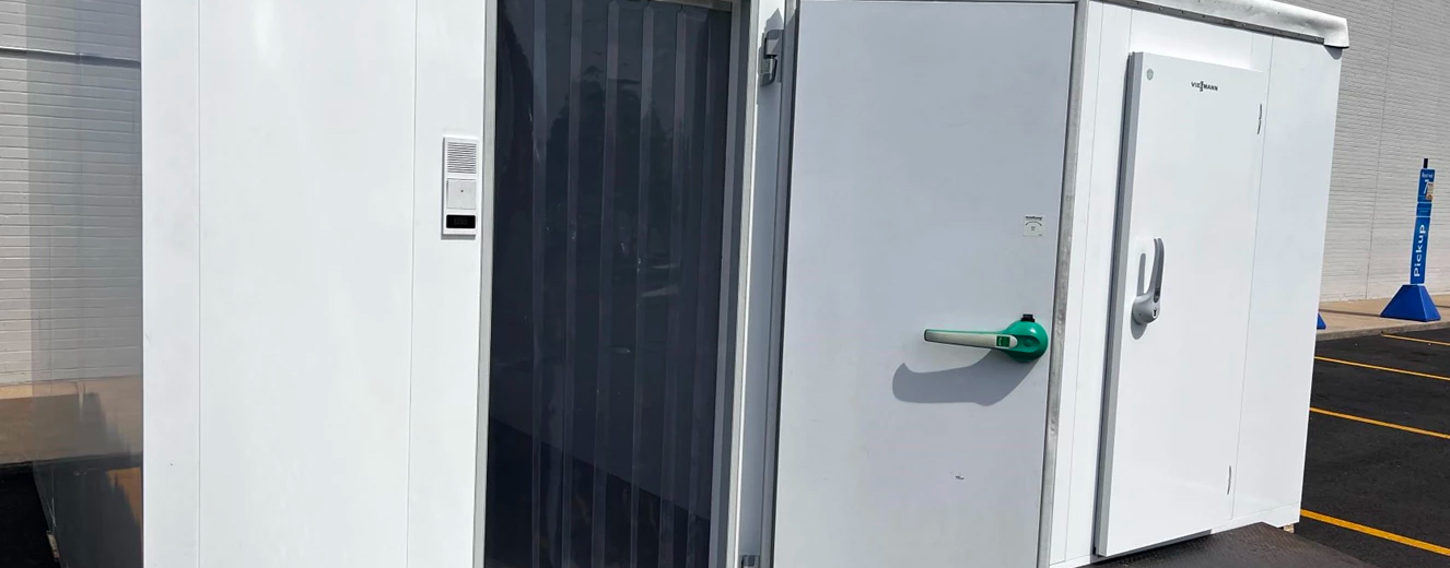 Cold room rental unit with a white exterior and a black curtain door, showcasing refrigeration features.