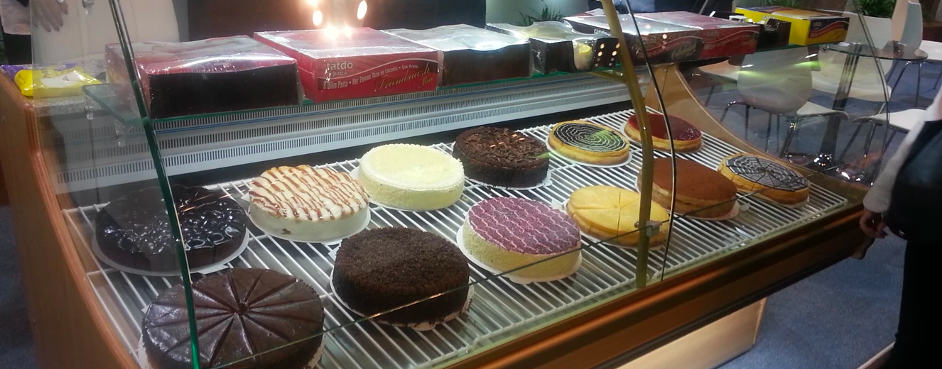 Assorted cakes in a display case, featuring chocolate, yellow, and purple textures at Gulfood Manufacturing.