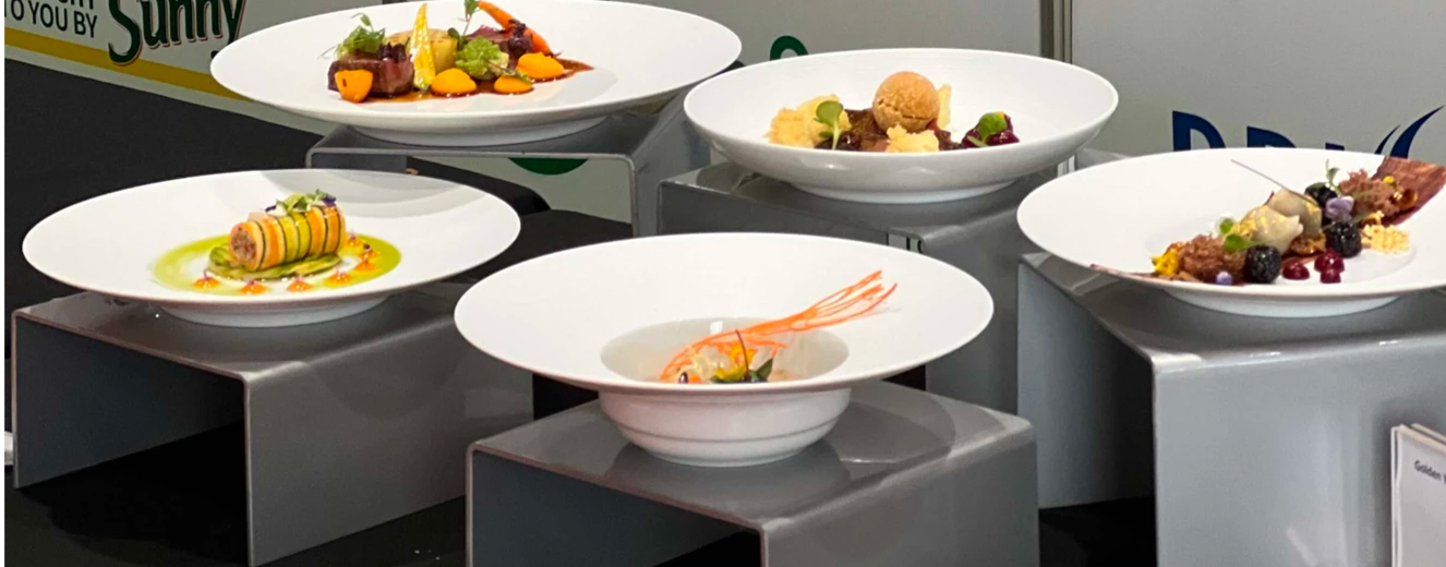 Elegant white bowls display gourmet dishes, featuring vibrant ingredients and a shrimp garnish.