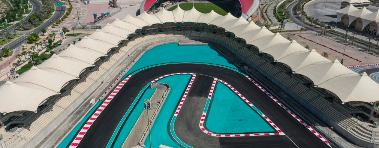 Aerial view of the Abu Dhabi Grand Prix circuit featuring turquoise track and red-and-white barriers.