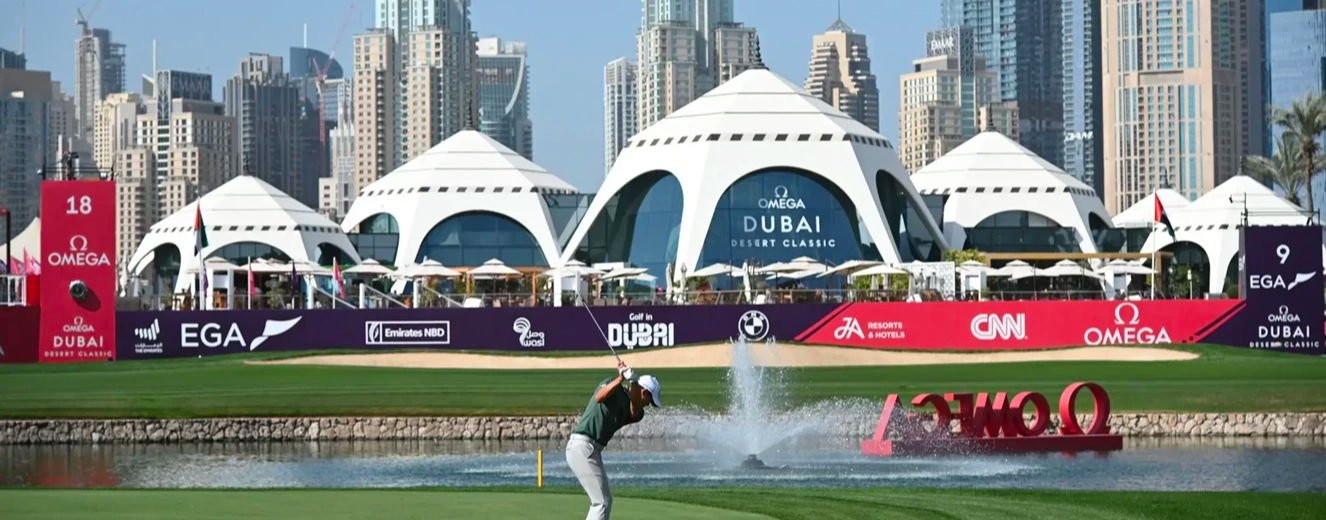 A golfer swings on a lush green course, with modern white tents and Dubai's skyline in the background.