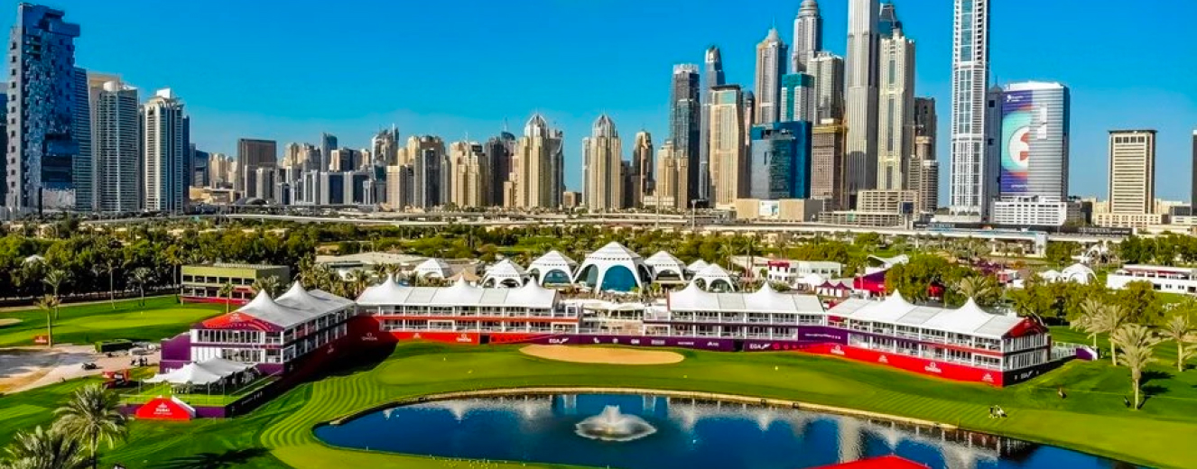 Dubai skyline with modern buildings, white event tents, and a reflective pond under a clear blue sky.