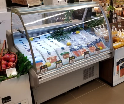 A glass-fronted display case filled with various seafood, featuring ice and green herbs.