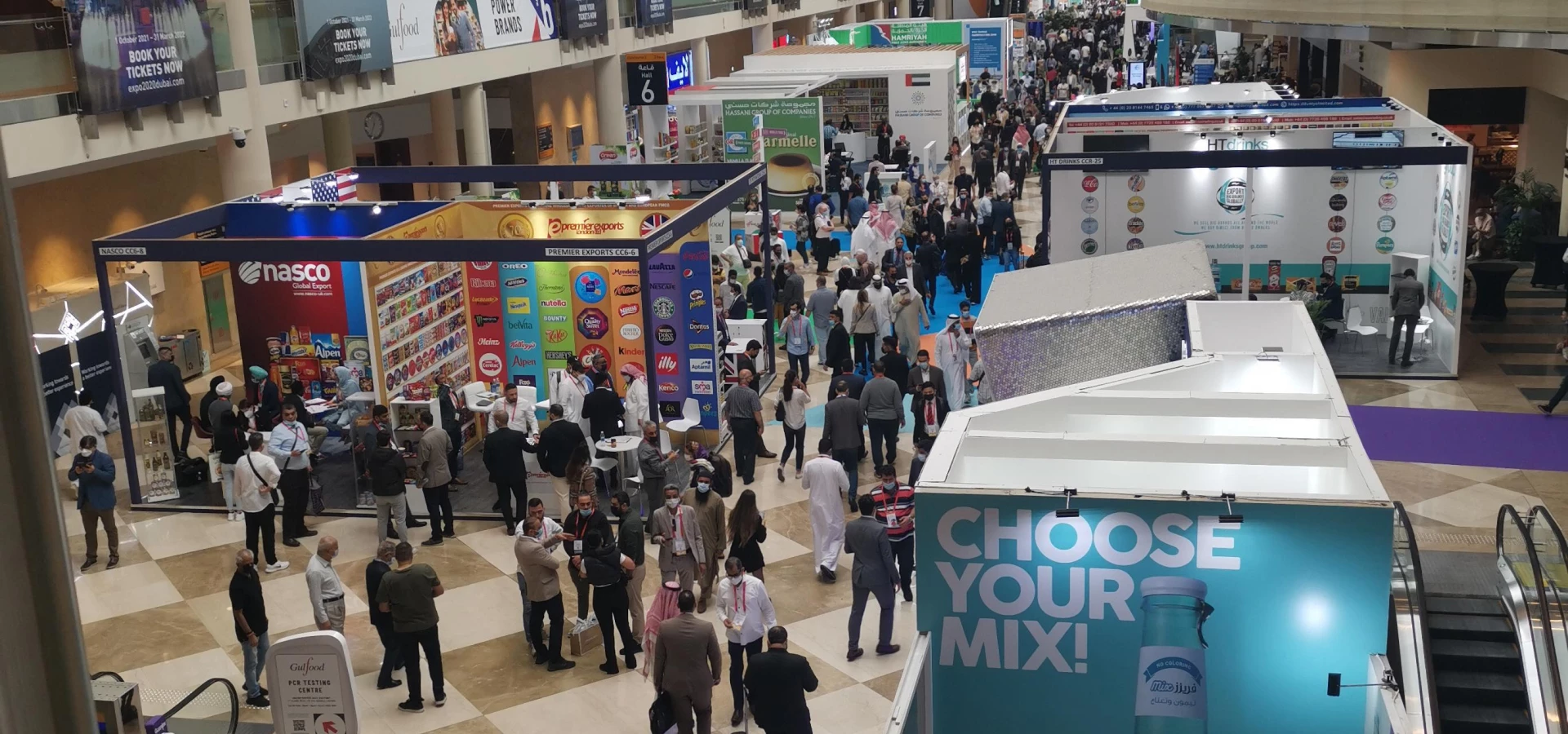 Crowd of attendees at an exhibition, with colourful booths and banners in the background.