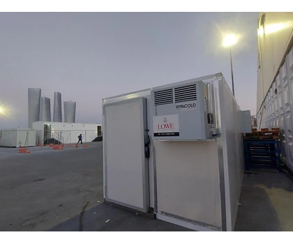White storage unit with a grey air conditioning unit, set against a twilight city skyline.