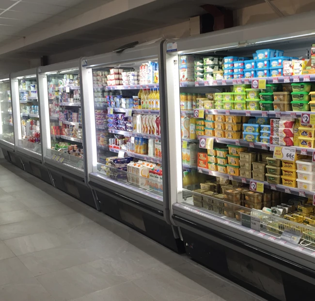 Supermarket freezer aisle displaying various colourful packaged food items in illuminated glass cases.