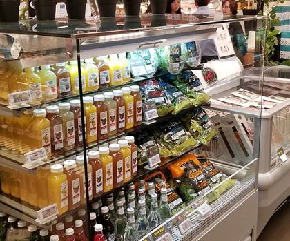 Chilled beverages and fresh produce displayed in a glass-fronted refrigerator, featuring vibrant colours.