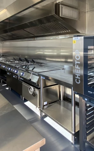 Stainless steel commercial kitchen equipment with blue accents, featuring multiple cooking stations and surfaces.