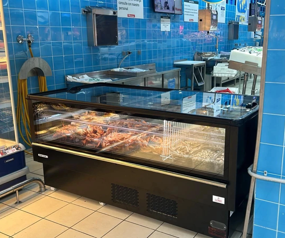 A black refrigerated display case showcasing various food items against a blue tiled background.