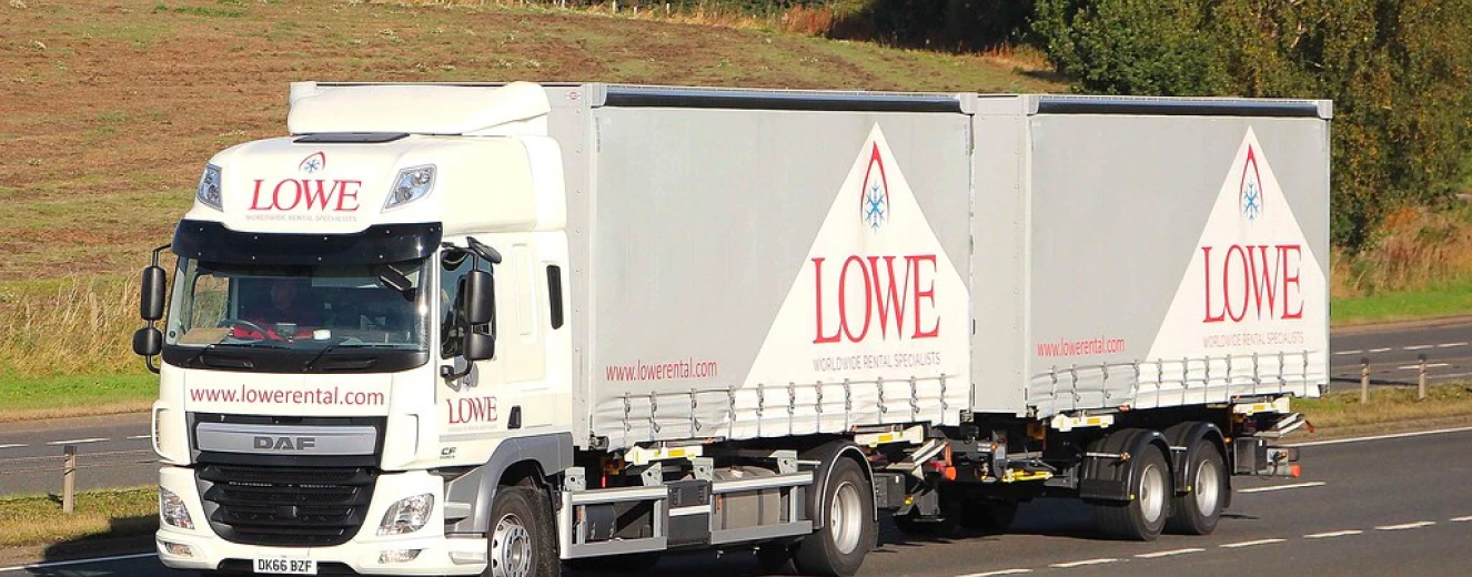 Grey truck with "LOWE" logo parked on a grassy area, showcasing a clear blue sky.