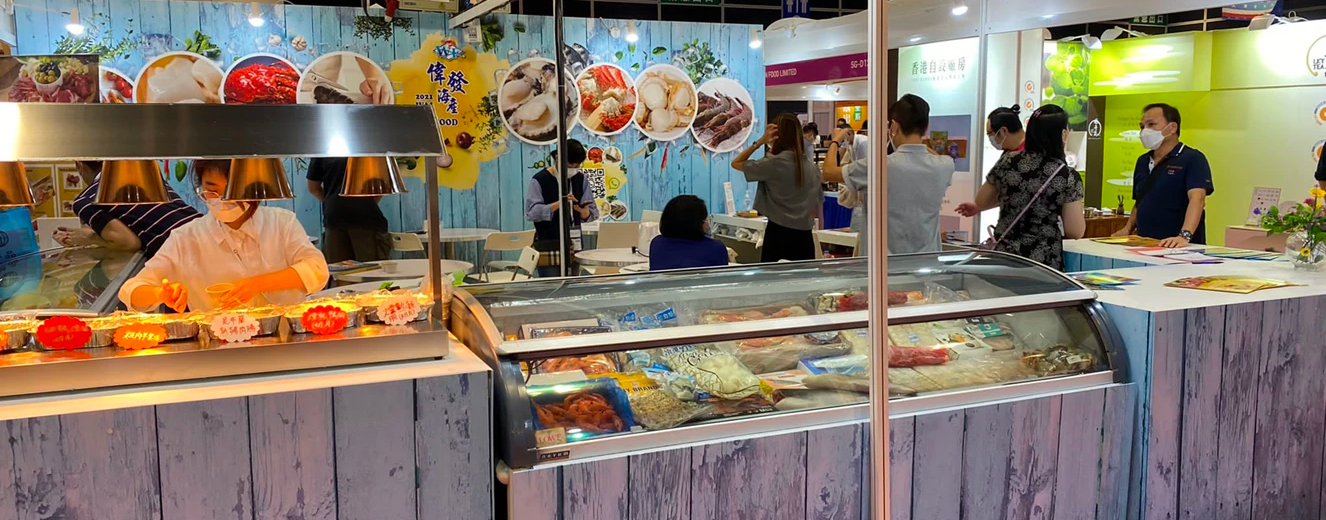 Ray Lee stands near a seafood display, with colourful posters and people in the background.