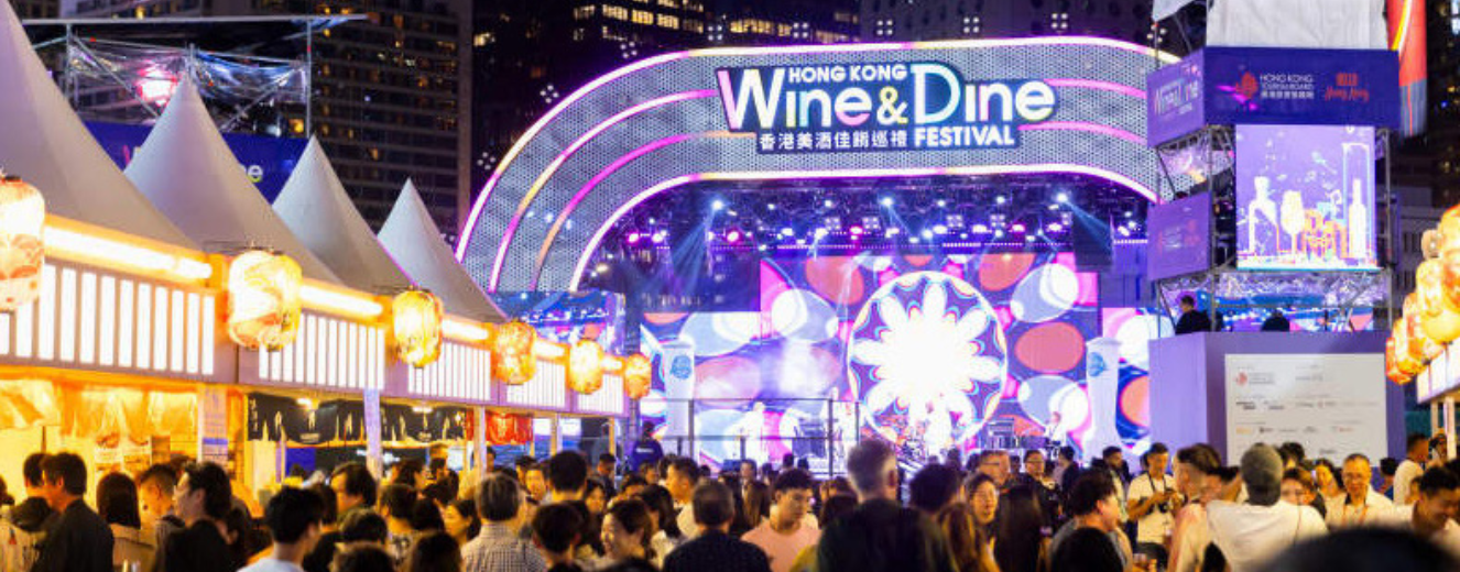 Crowd gathered at the vibrant Hong Kong Wine & Dine Festival, illuminated by colourful lights.