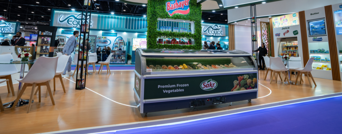 Showcase of a refrigerated display featuring vibrant vegetables, with a green, grass-like backdrop.