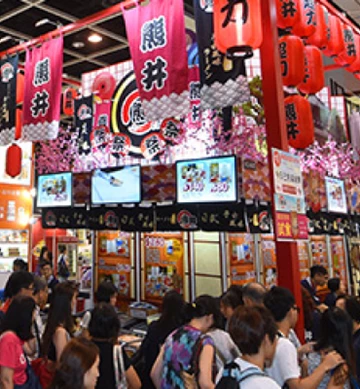 Vibrant festival stall with pink banners and lanterns, crowded with attendees enjoying the event.