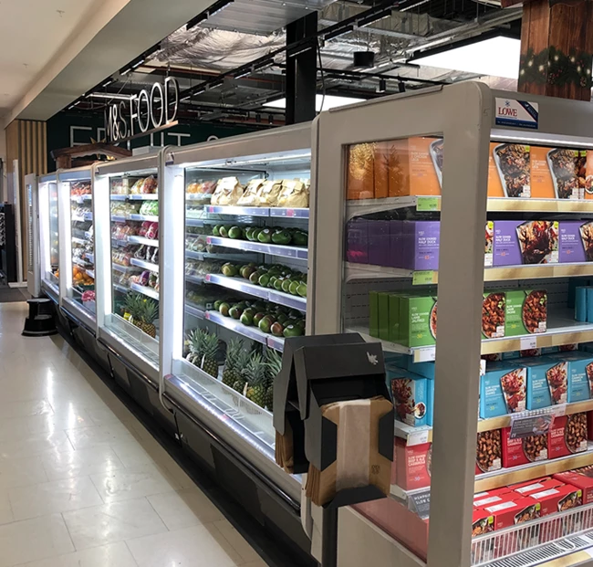 Chilled display cases filled with colourful packaged food items in a supermarket aisle.