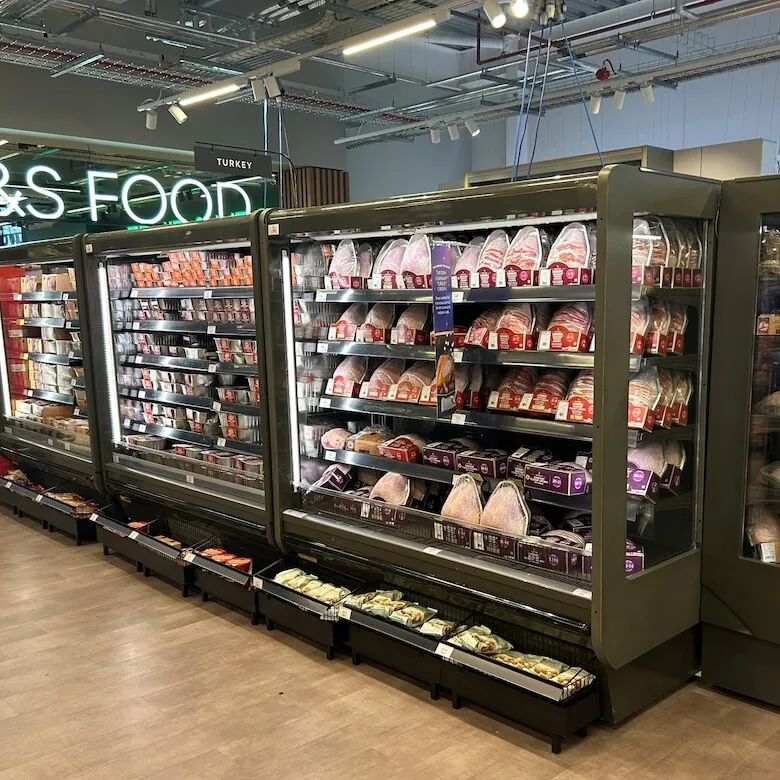 M&S Food display featuring various packaged meats and fresh produce in a modern retail environment.