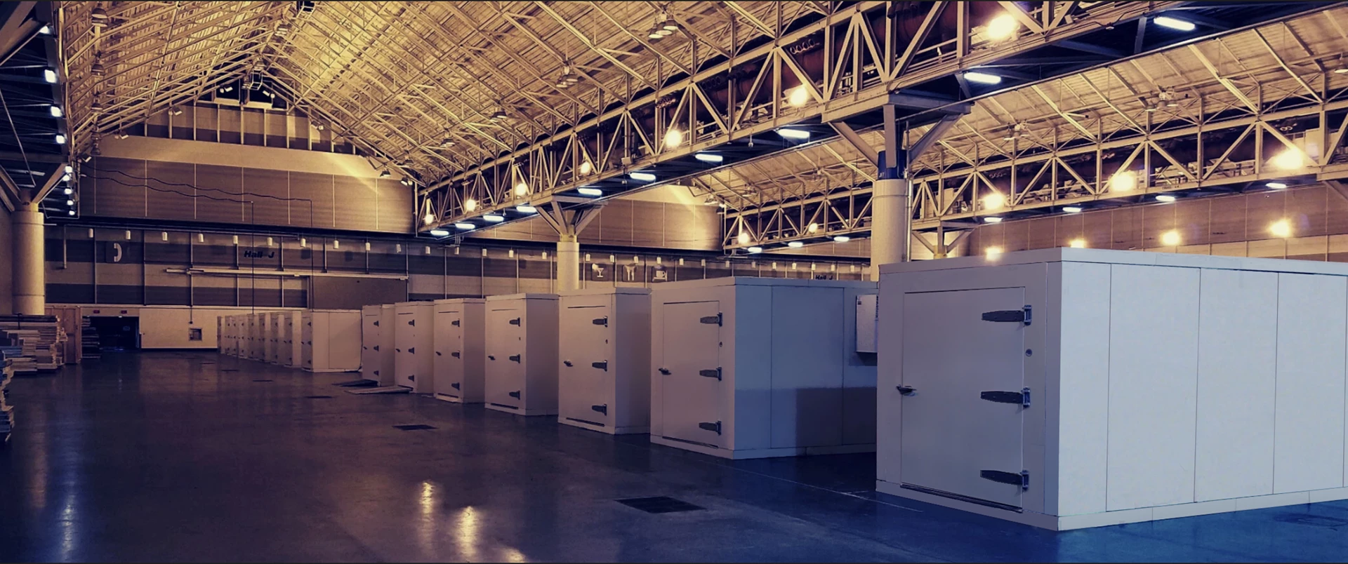 White cold storage units lined up in a spacious, well-lit industrial facility with a high ceiling.