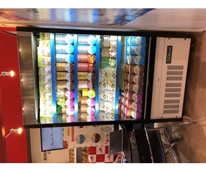Colourful display of ice cream tubs in a glass-fronted freezer at a food exhibition.