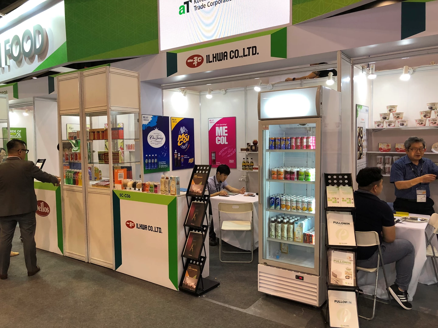 Exhibition booth featuring colourful product displays and a glass-fronted fridge at a food expo.