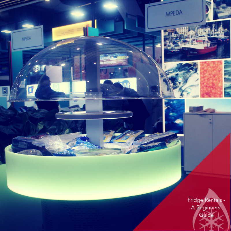 A transparent display dome showcases various items on a softly glowing circular base at an exhibition.