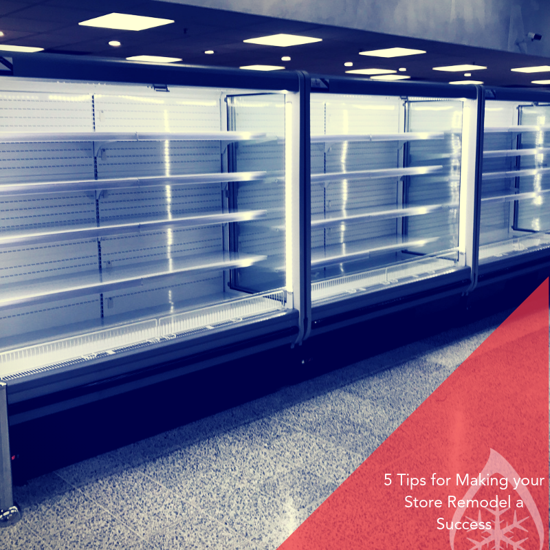 Empty refrigerated display cases with white shelves and a red carpet in a retail space.