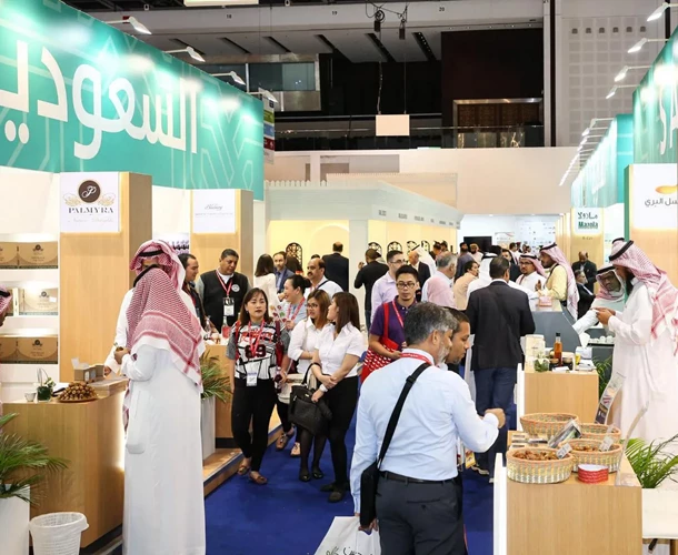 Crowd at a trade event featuring Saudi products, with green signage and wooden display stands.