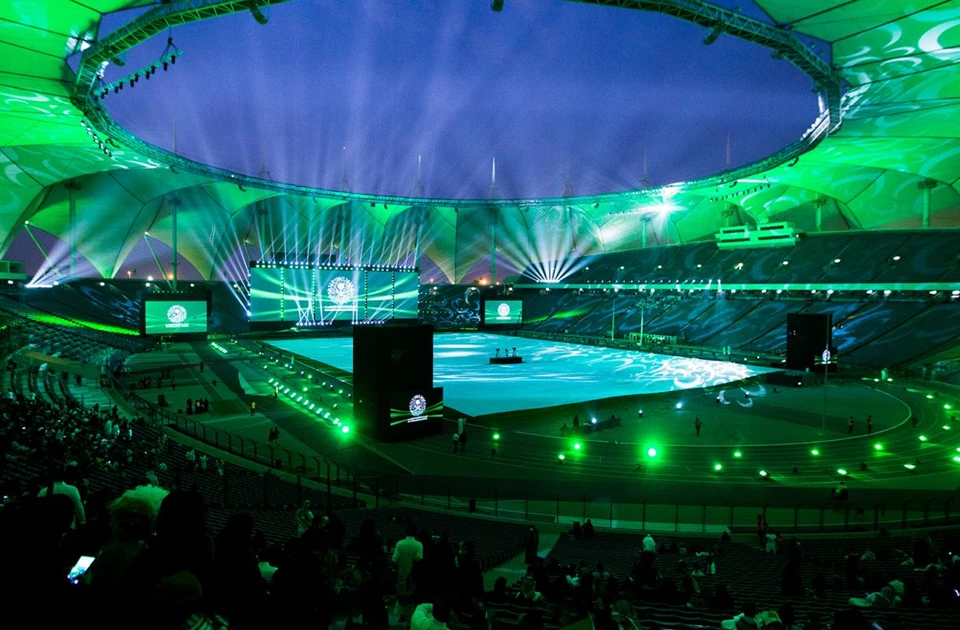The stadium is illuminated with green lights, showcasing a vibrant atmosphere for the event.