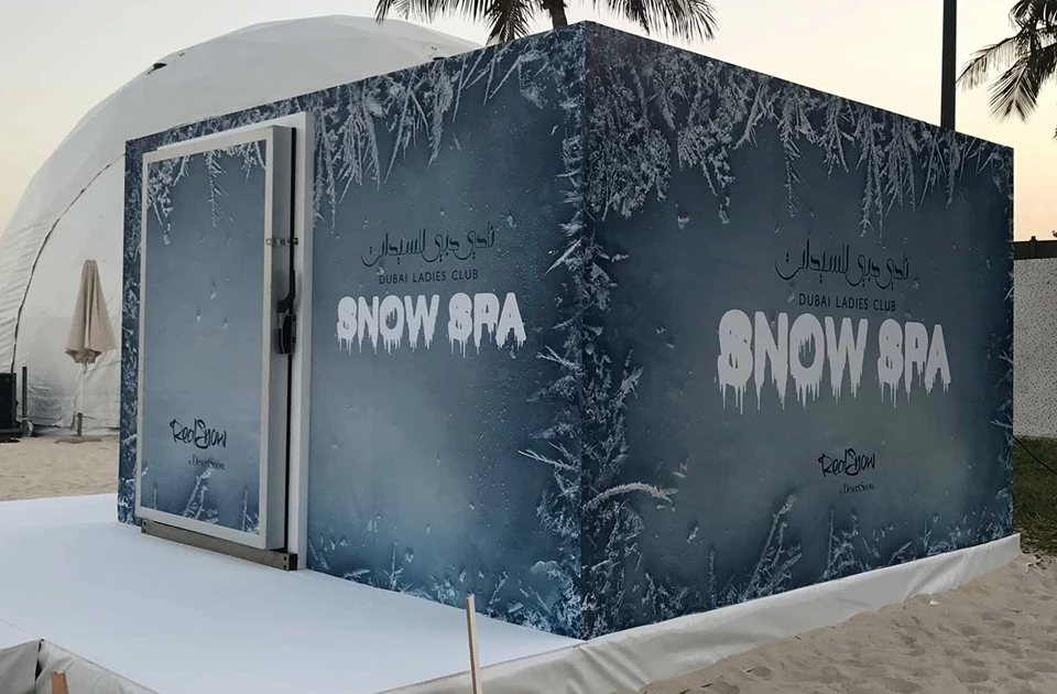 Snow Spa structure with icy blue design, featuring white lettering, set against a sandy background.