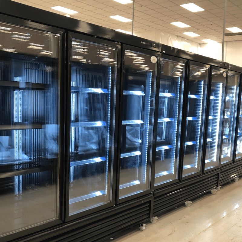 Black glass-fronted freezers with blue lighting, showcasing empty shelves in a retail setting.