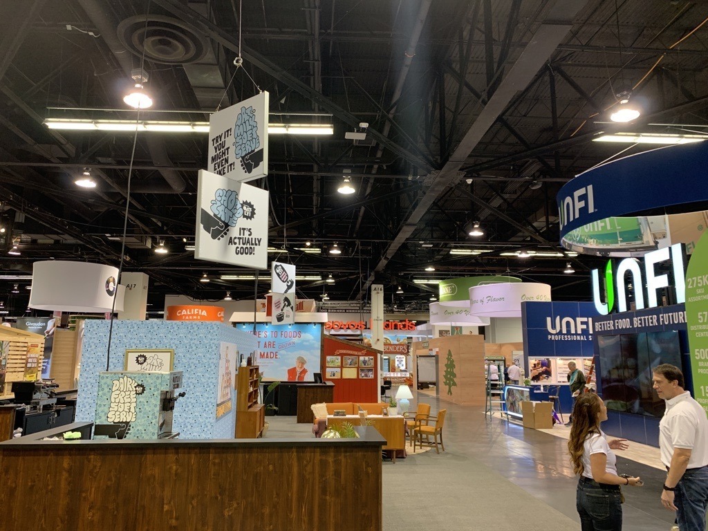 Expo showcase featuring various booths with bright banners and a spacious interior.