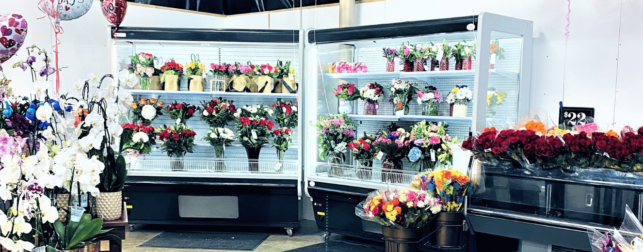 Floral arrangements in refrigerated displays, featuring vibrant colours, prepared for Valentine's Day sales.