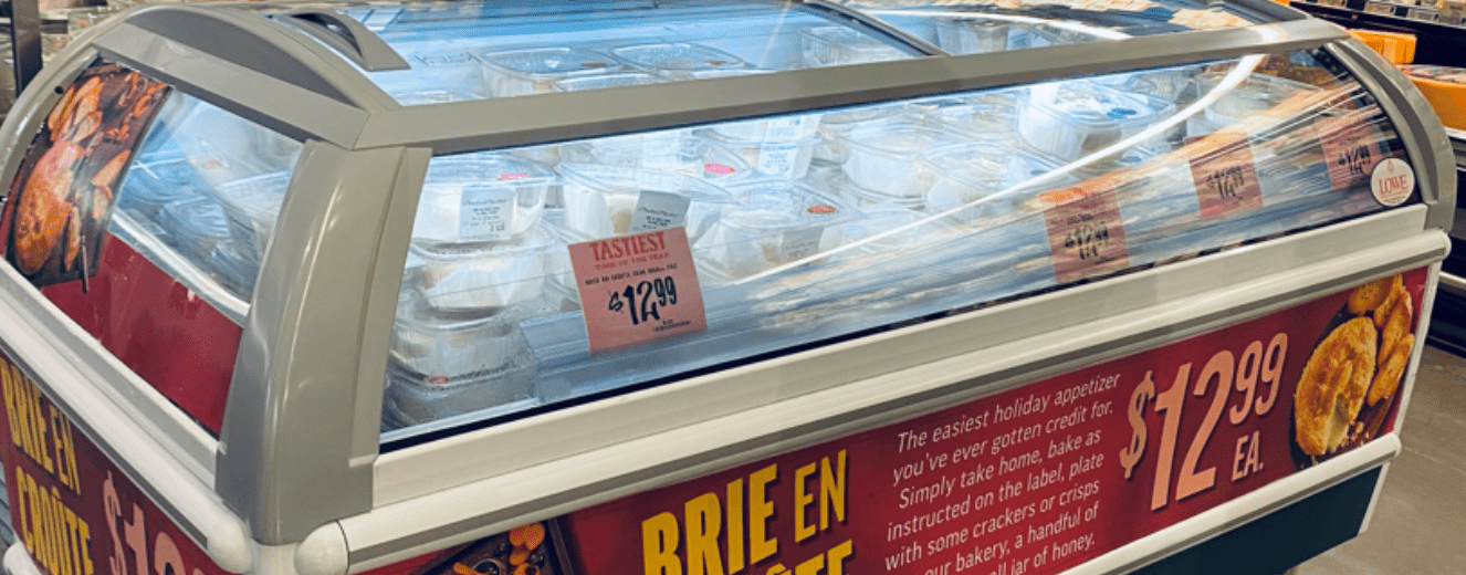 White cheese packages in a refrigerated display, with a red sale sign reading "$12.99".