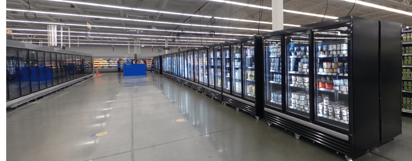 Row of black refrigerated display cases filled with products, set in a spacious retail environment.