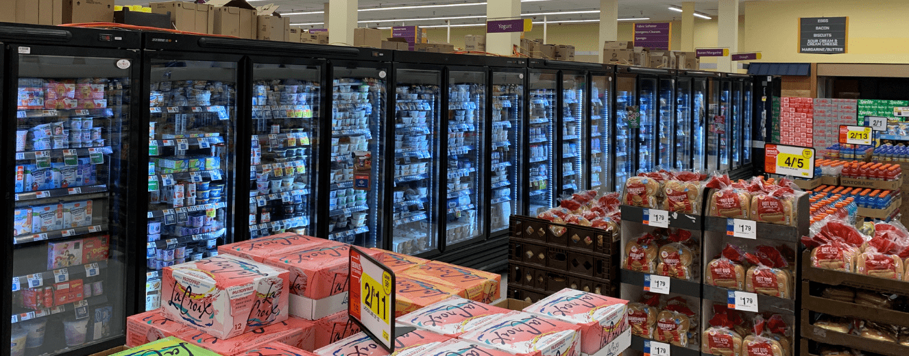 Refrigerated display cases filled with products, with colourful boxes stacked in the foreground.