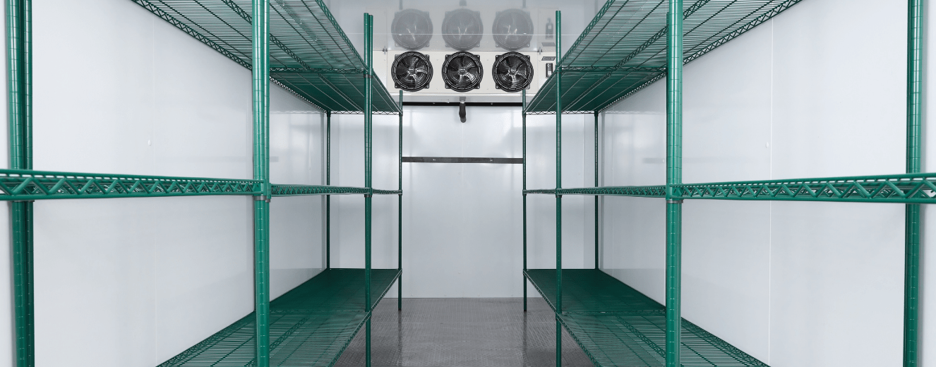 Cold storage facility featuring green metal shelving and industrial fans against a white background.