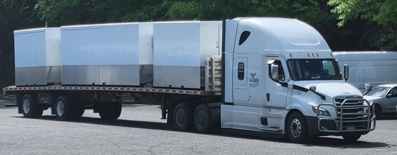 White refrigerated truck parked on asphalt, surrounded by greenery, indicating emergency refrigeration services.