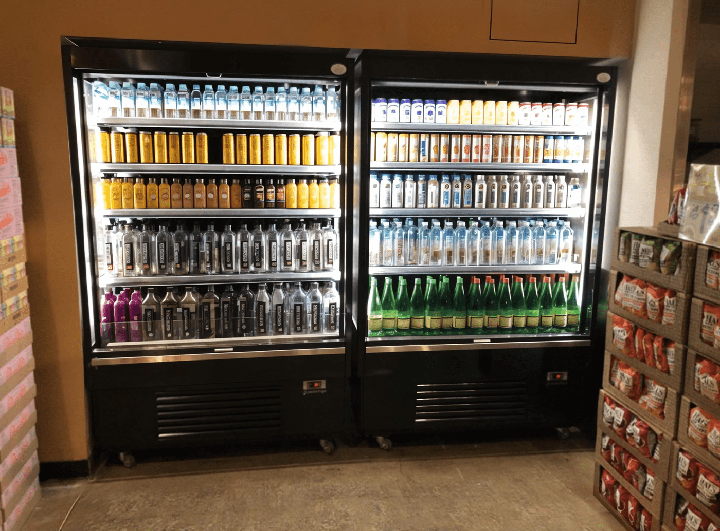 Two large beverage fridges filled with colourful drinks, including cans and bottles, in a retail setting.