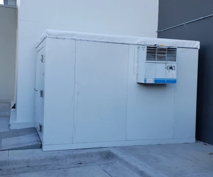 White exterior storage unit with an air conditioning unit mounted on the side.