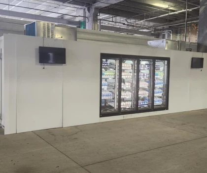 Vending machines with glass doors displaying various snacks, set against a white wall in a spacious venue.