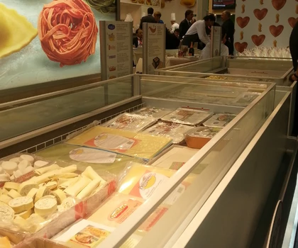 Display of various food items in a chilled showcase, featuring colourful packaging and a light background.
