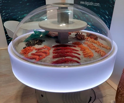A display of various seafood, featuring vibrant pink and orange shrimp under a glass dome.
