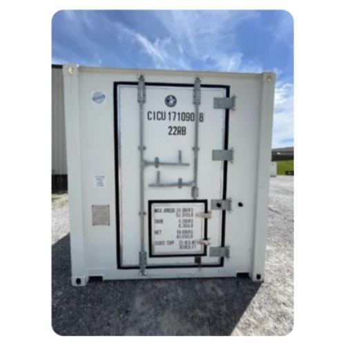 White container with black markings, featuring a secure door, set against a clear blue sky.