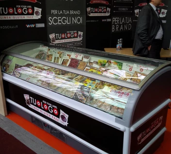 A glass-fronted ice cream display filled with various flavours, set against a dark exhibition backdrop.