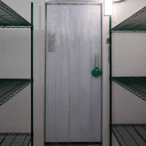Walk-in cooler with a white door and green handle, surrounded by metal shelves.