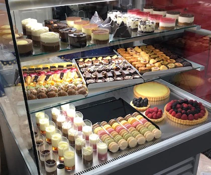 A display of assorted desserts, featuring colourful cakes, pastries, and creamy desserts in a glass case.