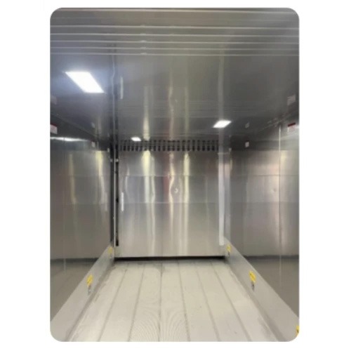Interior of a pre-built container room with shiny silver walls and a white floor.