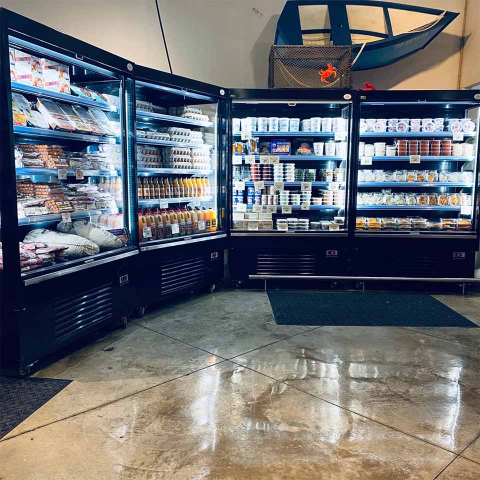 Three curved display fridges filled with various products, illuminated against a polished concrete floor.
