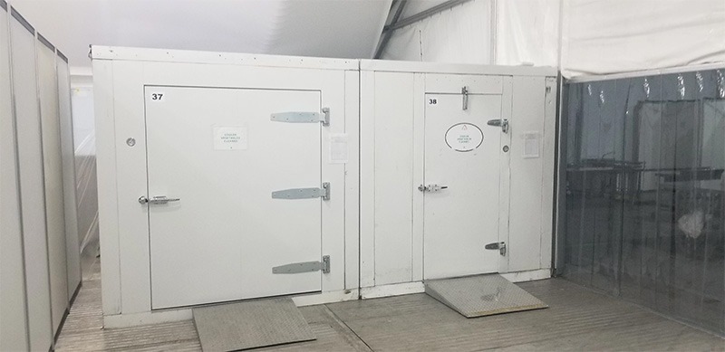 White cold storage units with metal doors, set against a neutral background in a retail environment.