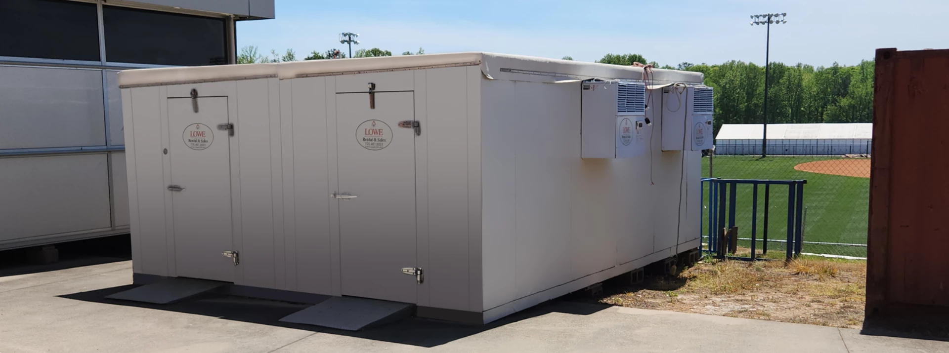 A grey storage unit with a door and ventilation, set against a clear blue sky.