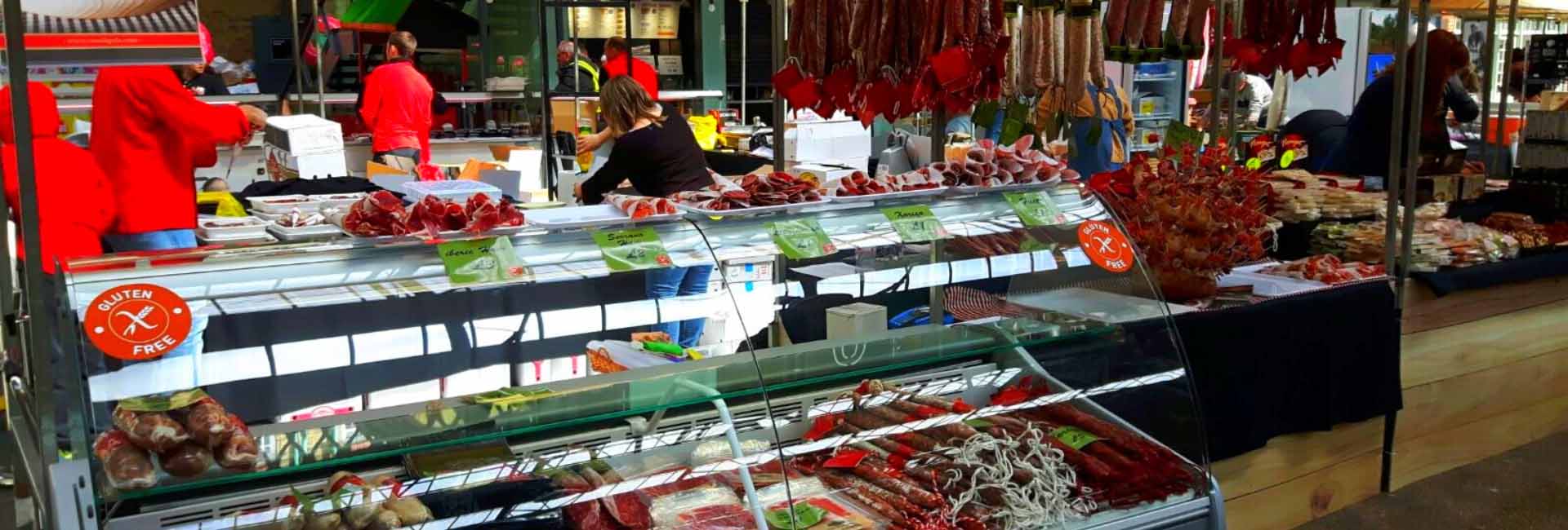 A variety of cured meats displayed in a market stall, with vibrant red and pink hues.